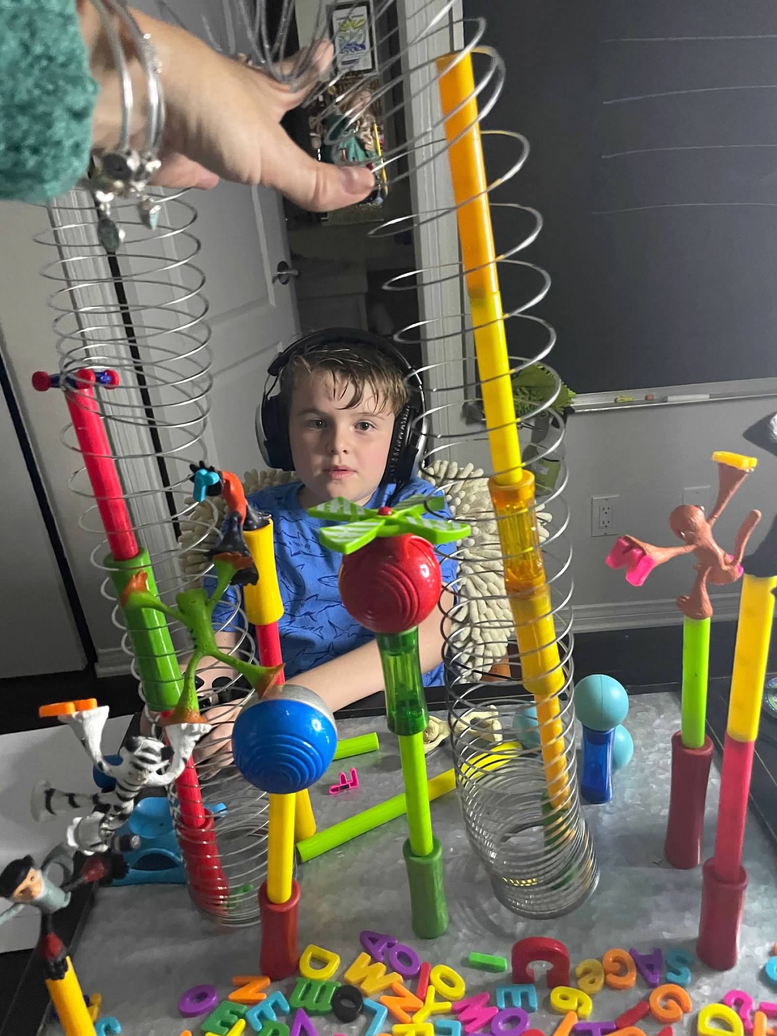 Boy with headphones surrounded by colorful marble run toys