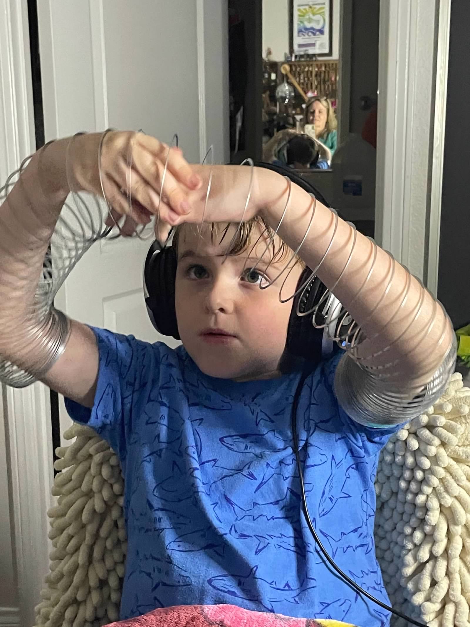 Boy playing with slinky on his arms wearing headphones