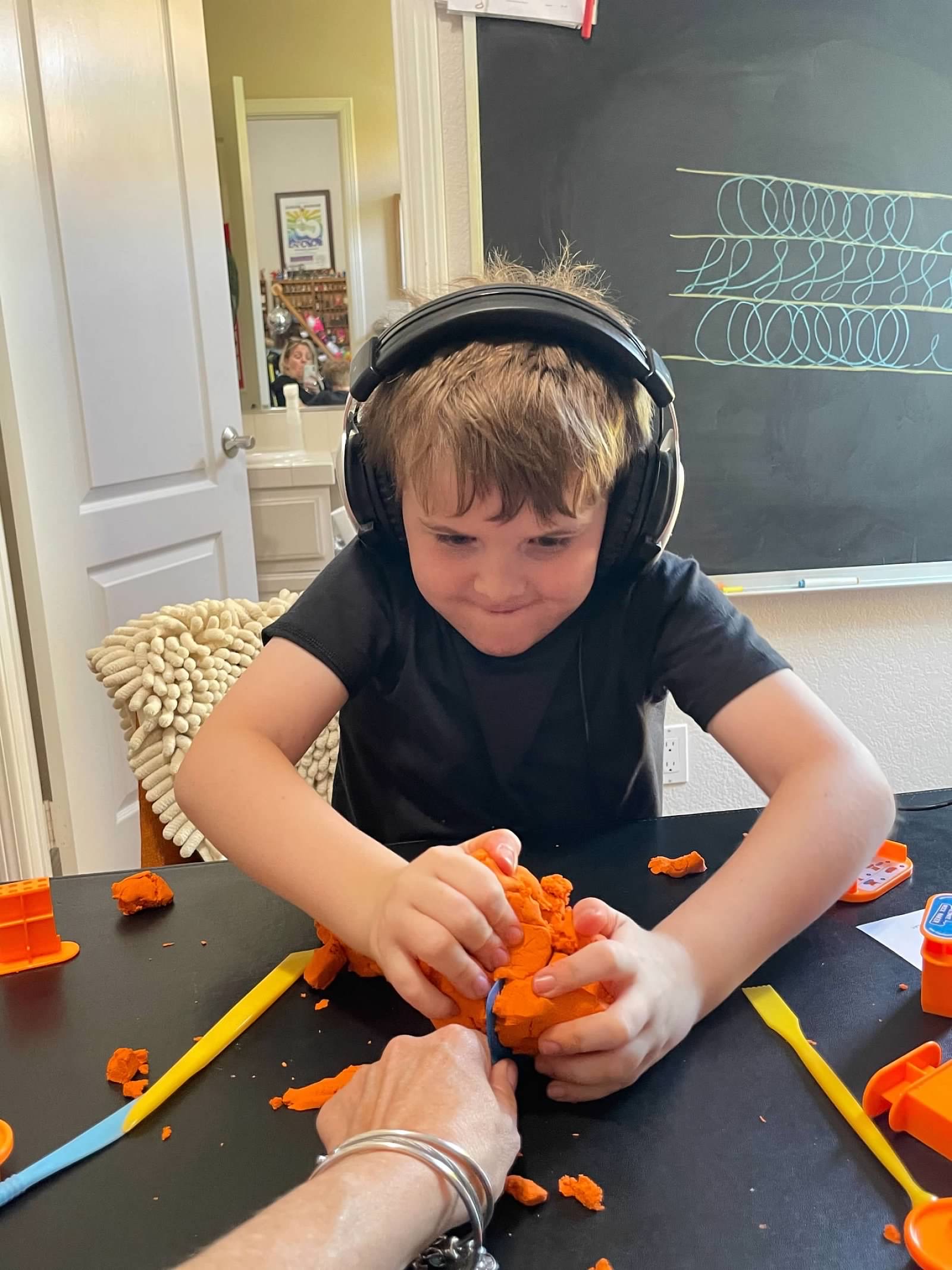 Student working orange kinetic sand with Susan