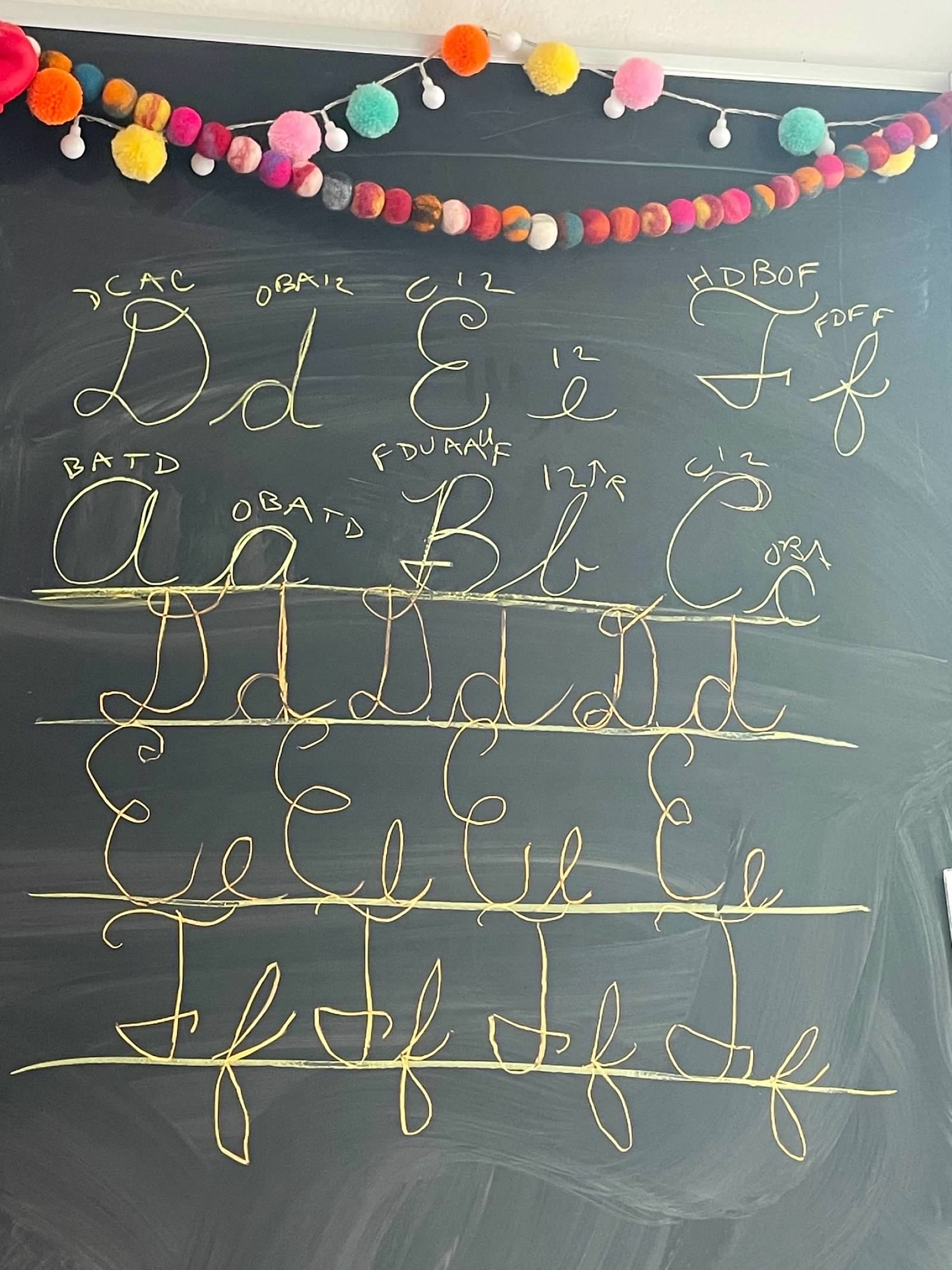Cursive chalkboard with colorful pom-pom garland