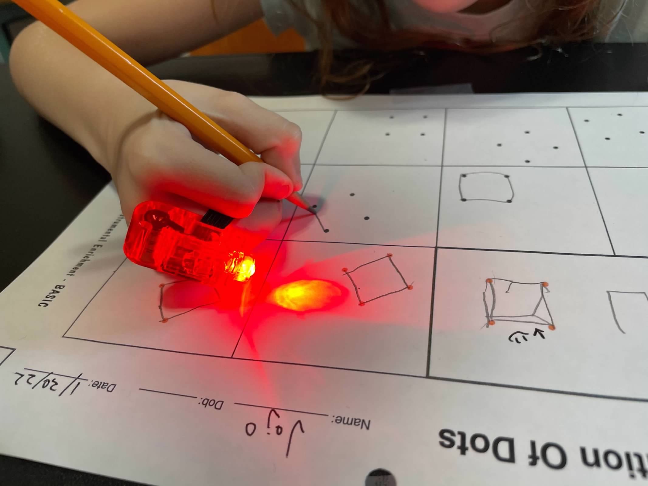 Child doing Organization of Dots with red light pencil