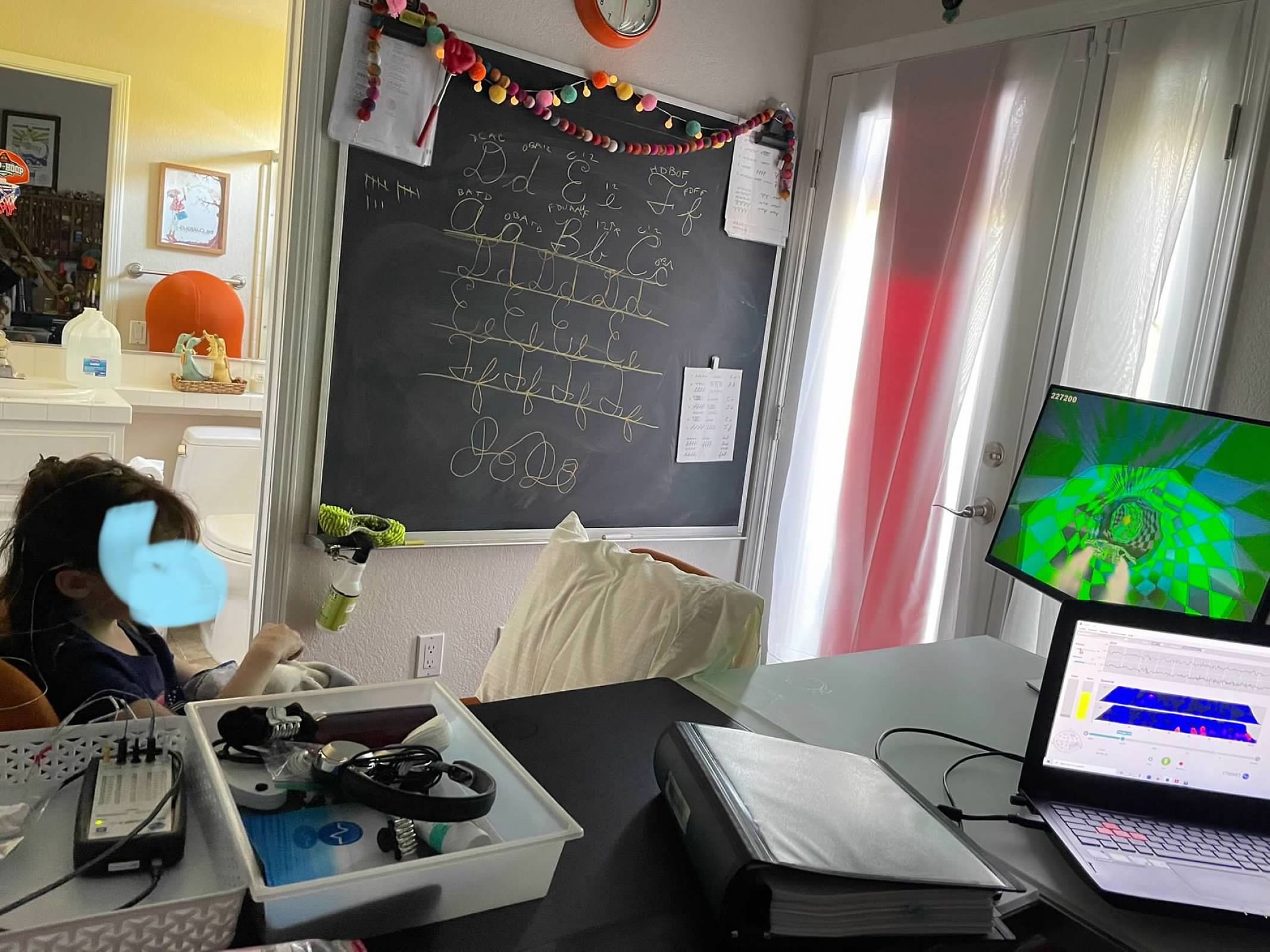 Child in neurofeedback session with EEG sensors and brain game on screen