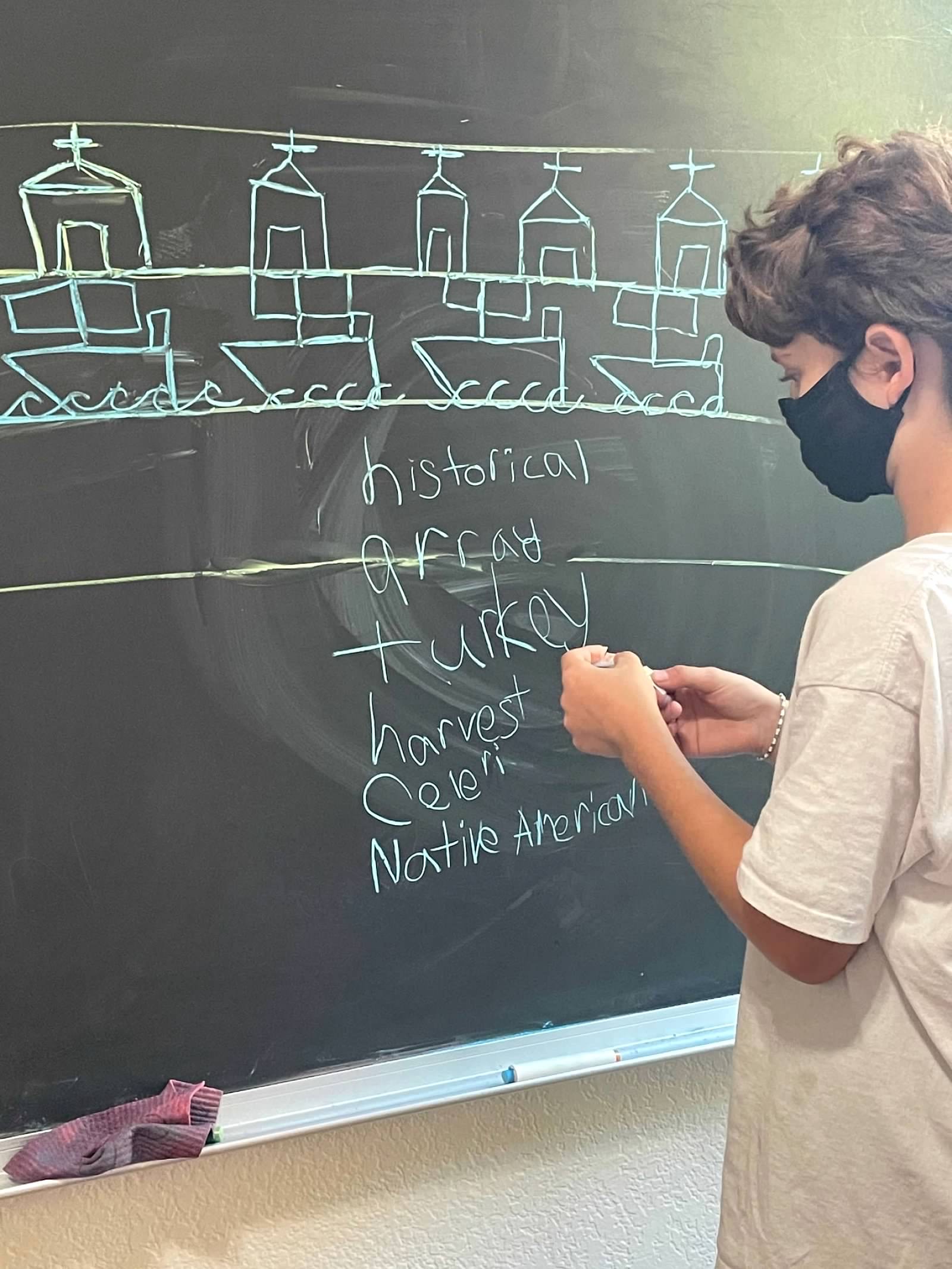 Student writing words at chalkboard